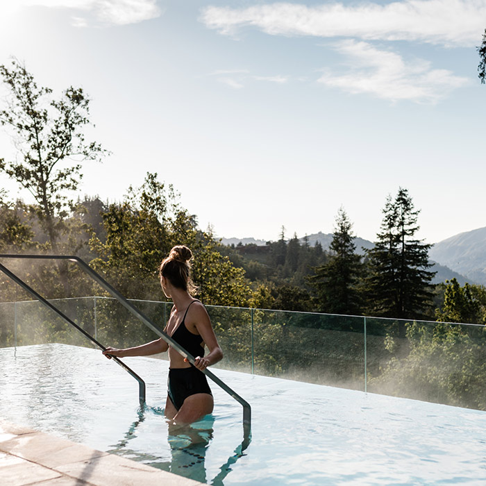 A woman relaxing in the resort pool area and looking at the forest views