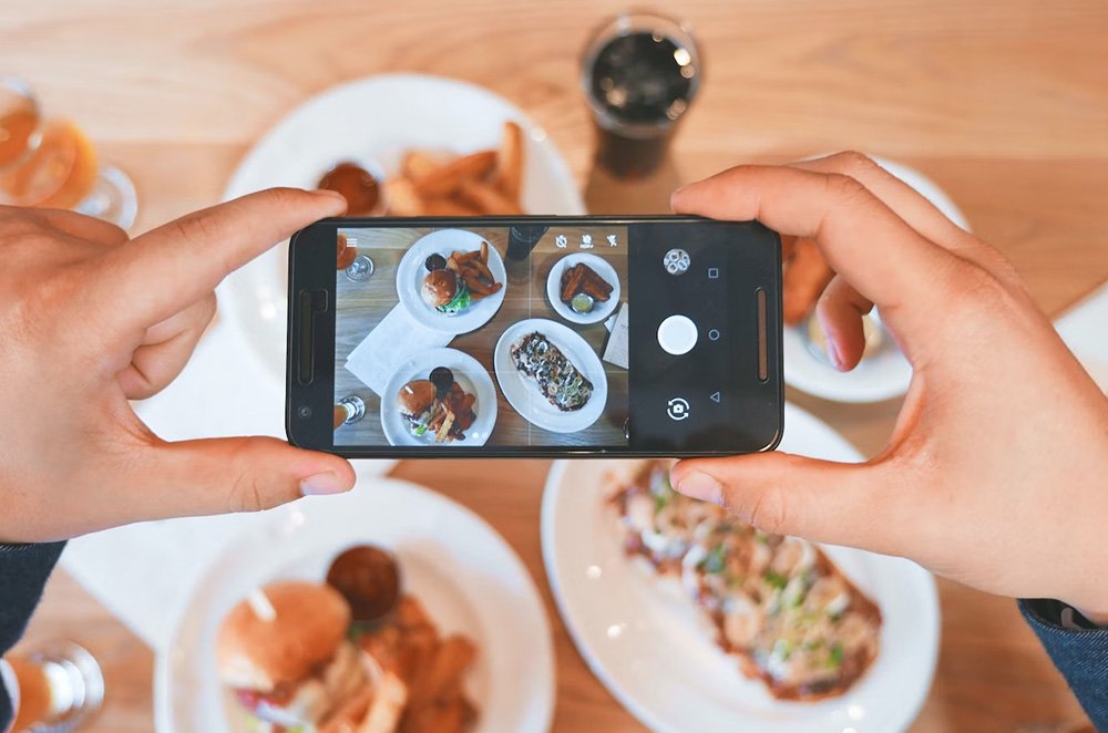 A woman taking a picture of delectable dishes and refreshing drinks served at a hotel restaurant